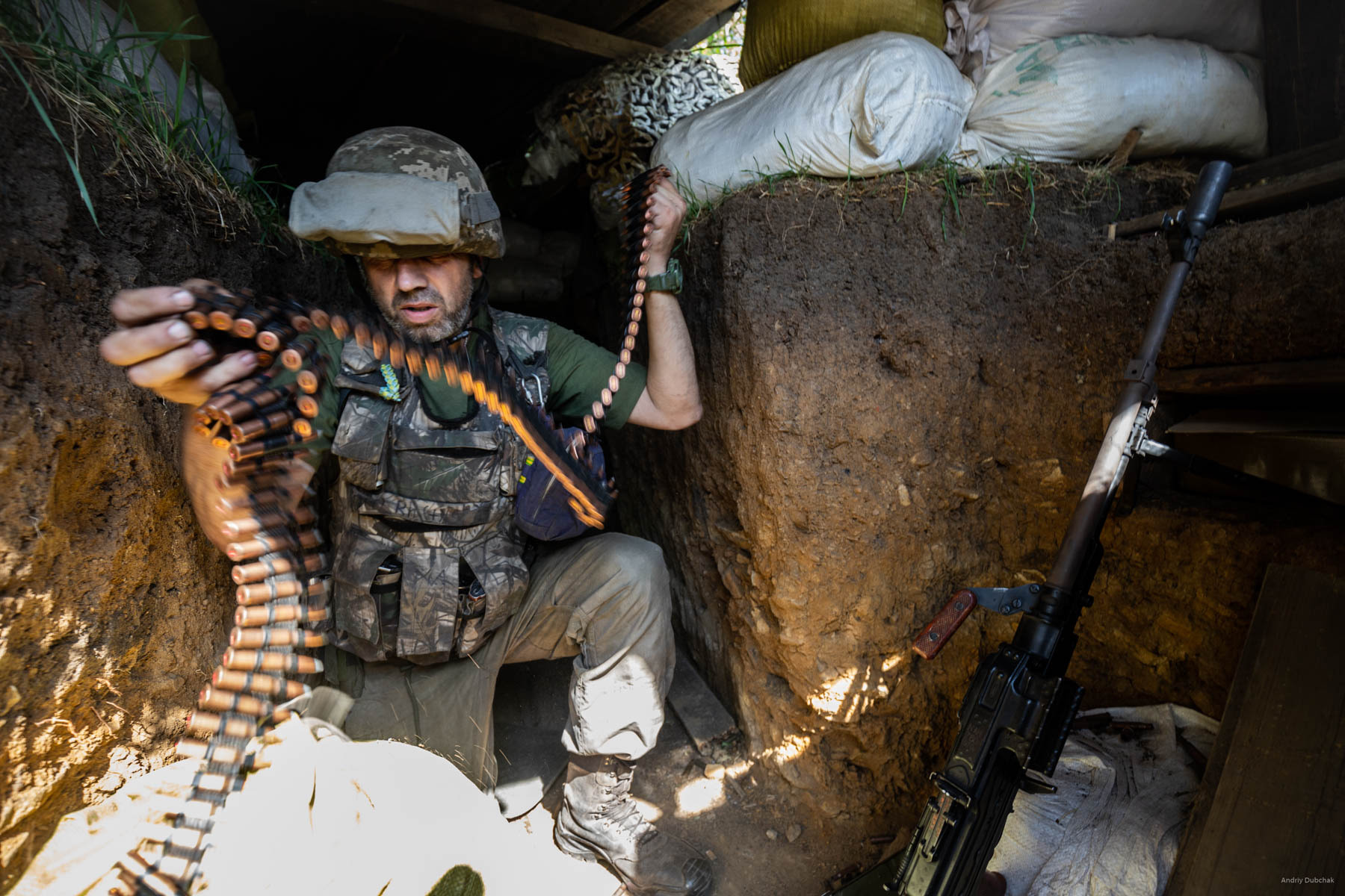 The enemy began to shoot back from infantry weapons. A Kalashnikov’s machine gun joins DSHK in the firefight. Bullets buzz and squeal above our position. The warriors strive to spare the rounds, but the rate of fire grows and machinegun belts are replaced (in the photo). Settlement Pivdenne, near Gorlivka on June, 17th, 2018   