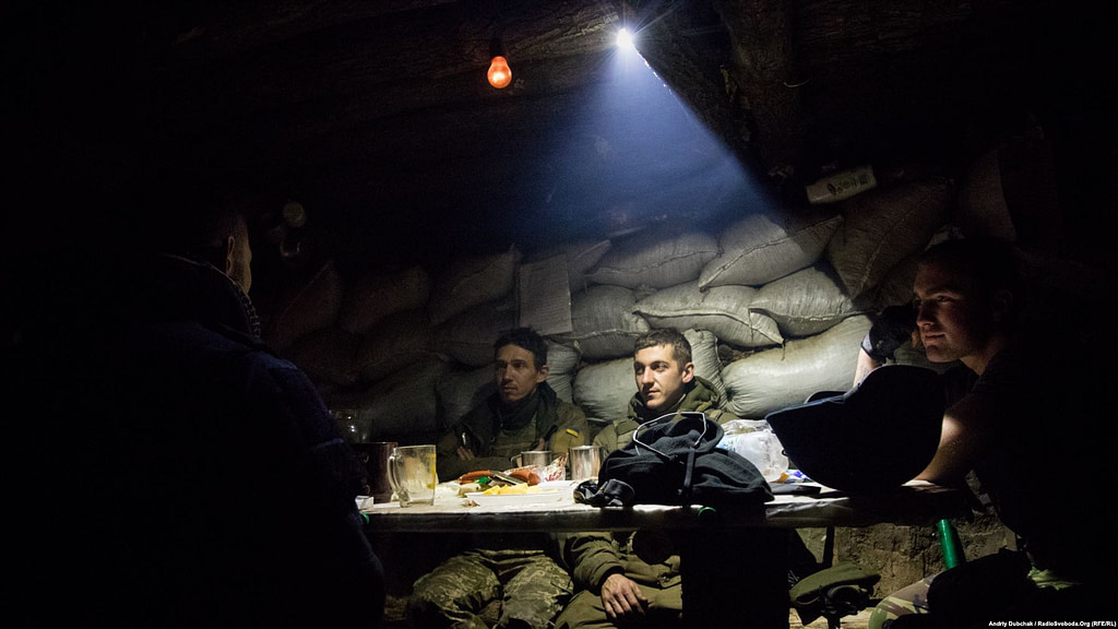 At a position near Bakhmut, Ukrainian soldiers eat dinner as their comrades-in-arms trade bursts of fire with Russia-backed separatists. Photographer Andriy Dubchak