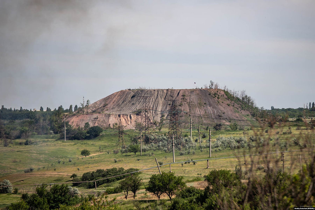 The smoke from burning houses drifts above a mine’s slag heap. On the summit, the flag of the Russia-backed separatists can be seen, where gun placements hold a commanding view of the battleground. Photo: Andriy Dubchak