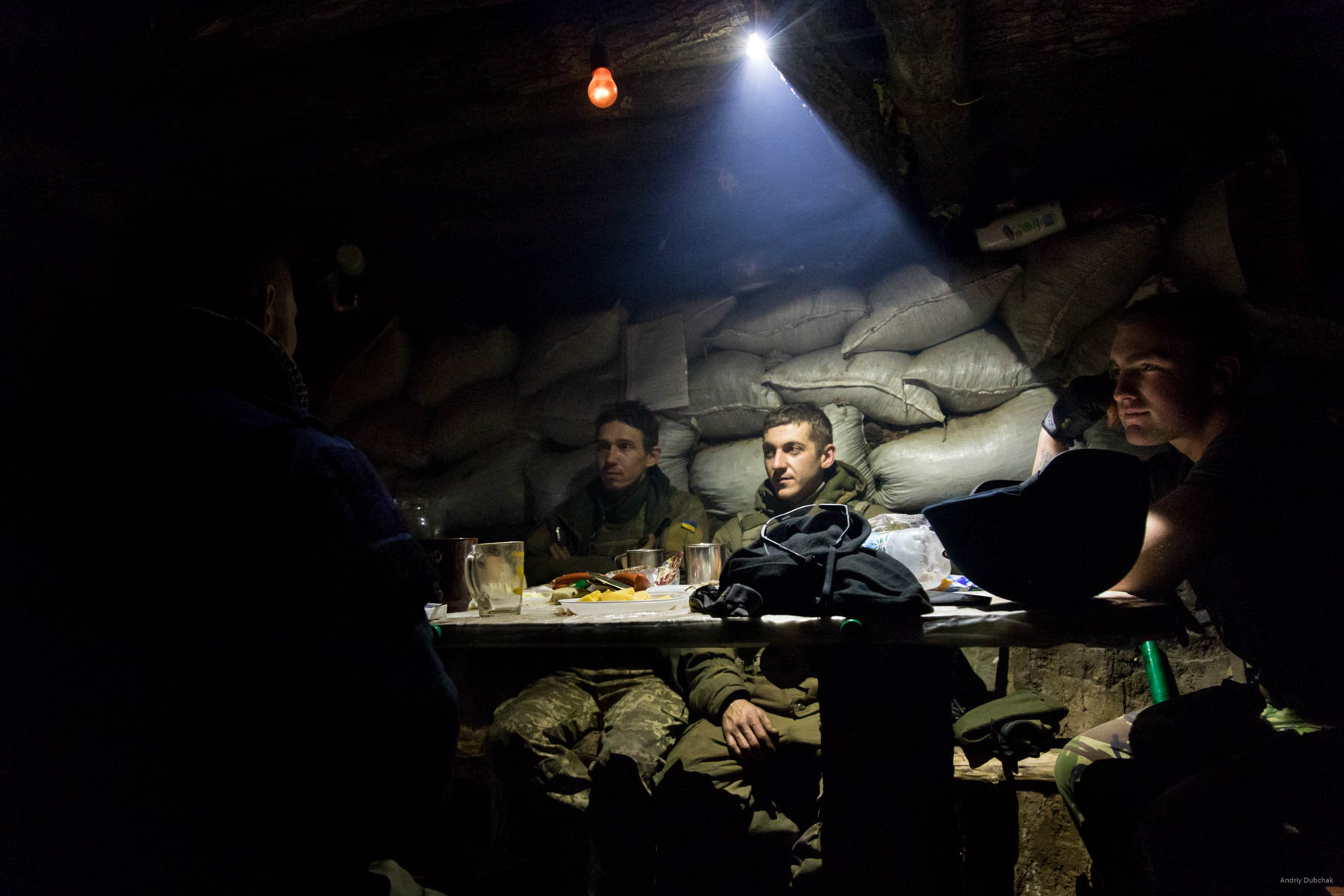 Supper during a fight. Ukrainian soldiers dine in a dugout on the front, near Popanskaya, while other fighters suppress the enemy's fire. The enemy, in some way, learned about our arrival to the position (it was found out from the radio interception). That night, we were shot at three times from small arms. District of Popasnoy, December 2017 Read and watch: https://goo.gl/SeMPXb
